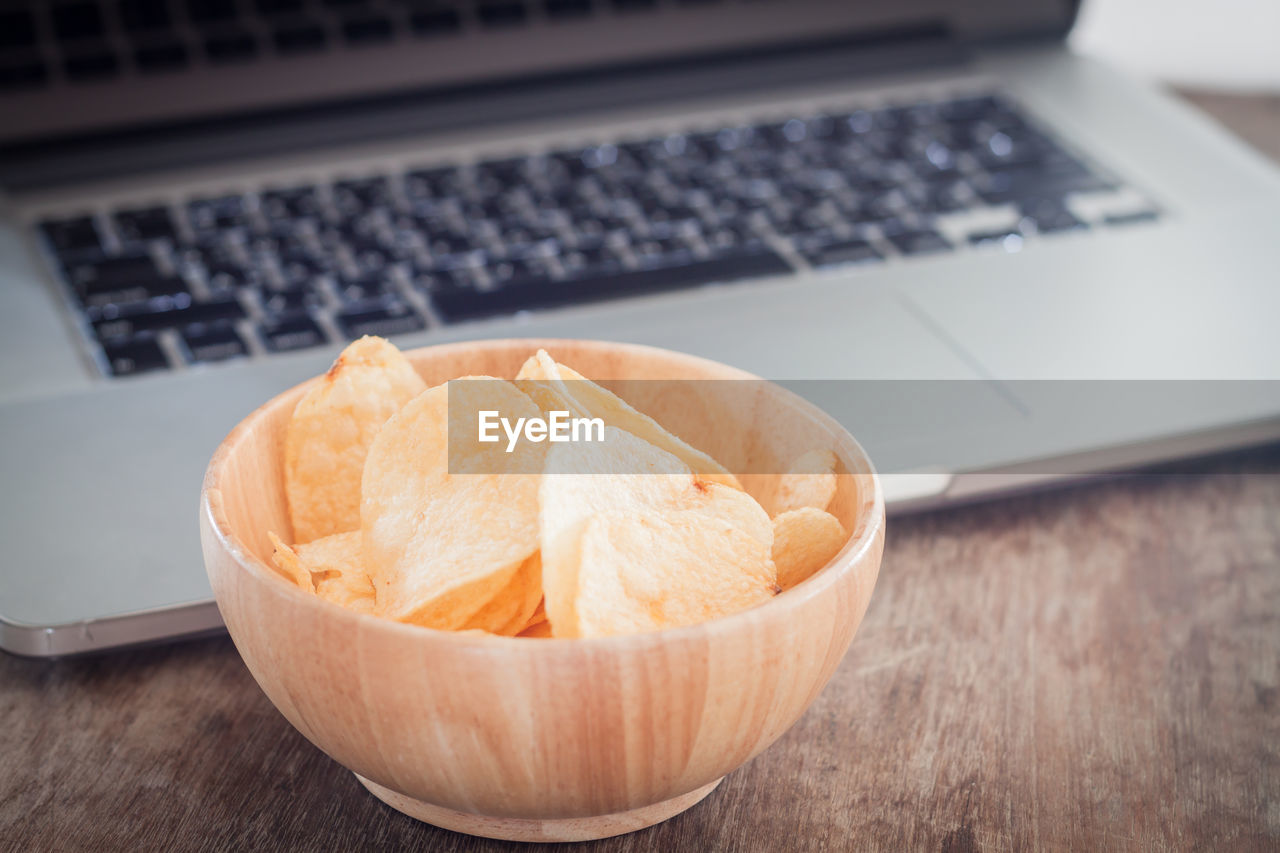 Close-up of wafers in bowl against laptop on table
