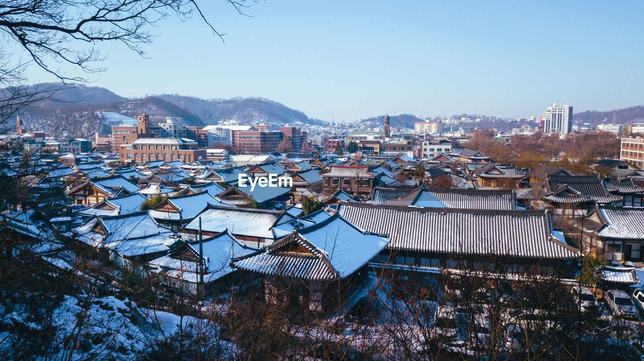 High angle view of houses and trees against blue sky