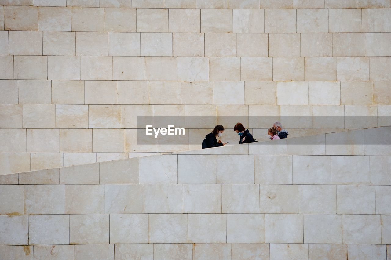 HIGH ANGLE VIEW OF PEOPLE WALKING ON COBBLESTONE