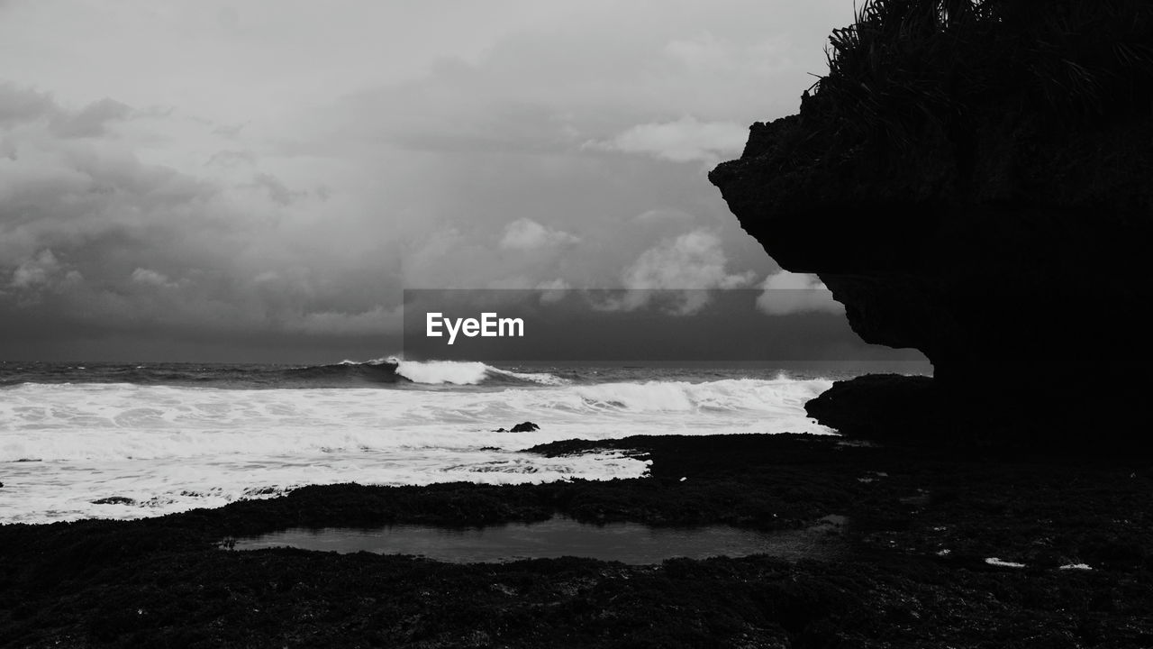 water, sea, coast, black and white, rock, land, ocean, monochrome photography, sky, beach, monochrome, wave, cloud, beauty in nature, darkness, nature, scenics - nature, horizon, shore, black, environment, wind wave, tranquility, outdoors, bay, body of water, silhouette, rock formation, no people, motion, horizon over water, non-urban scene, day, travel destinations, tranquil scene, coastline, sports, travel