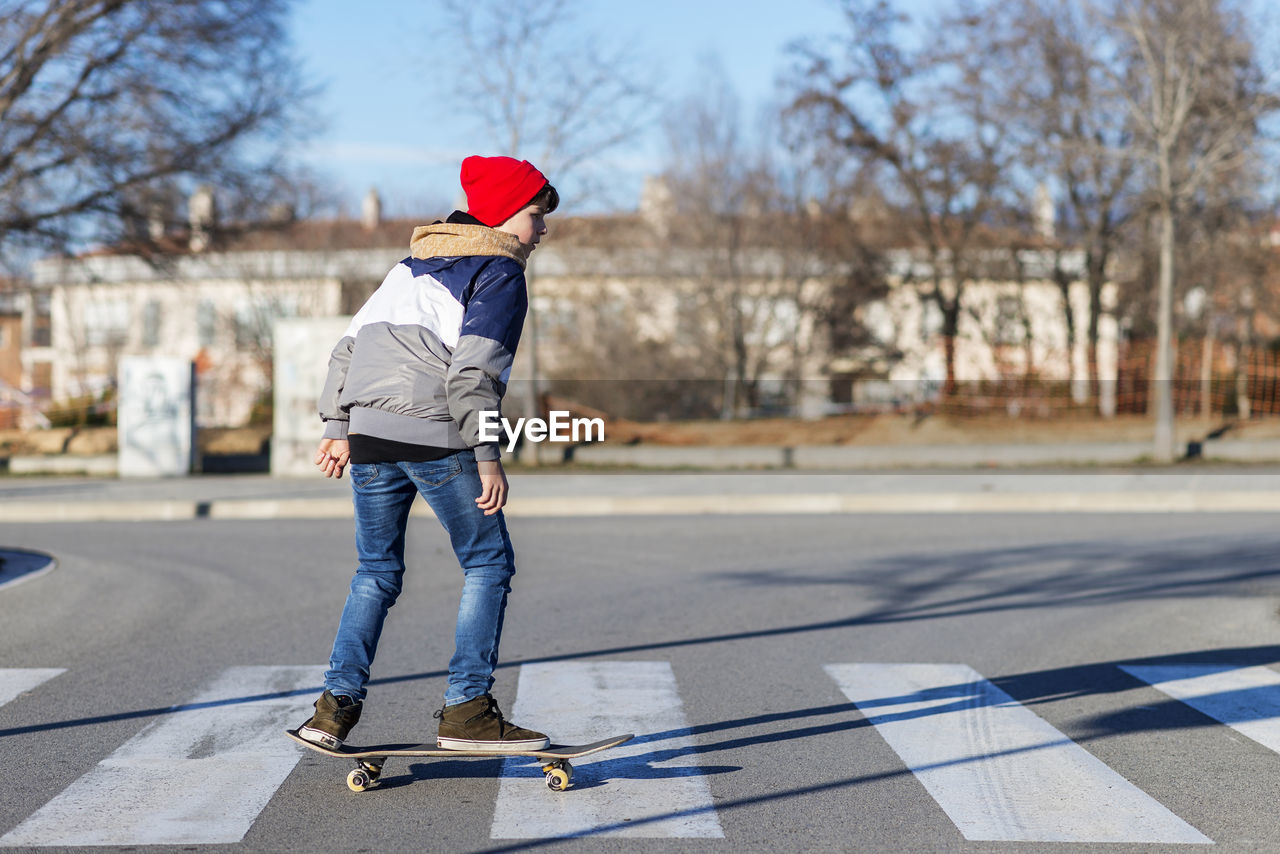 Rear view of boy skating on road