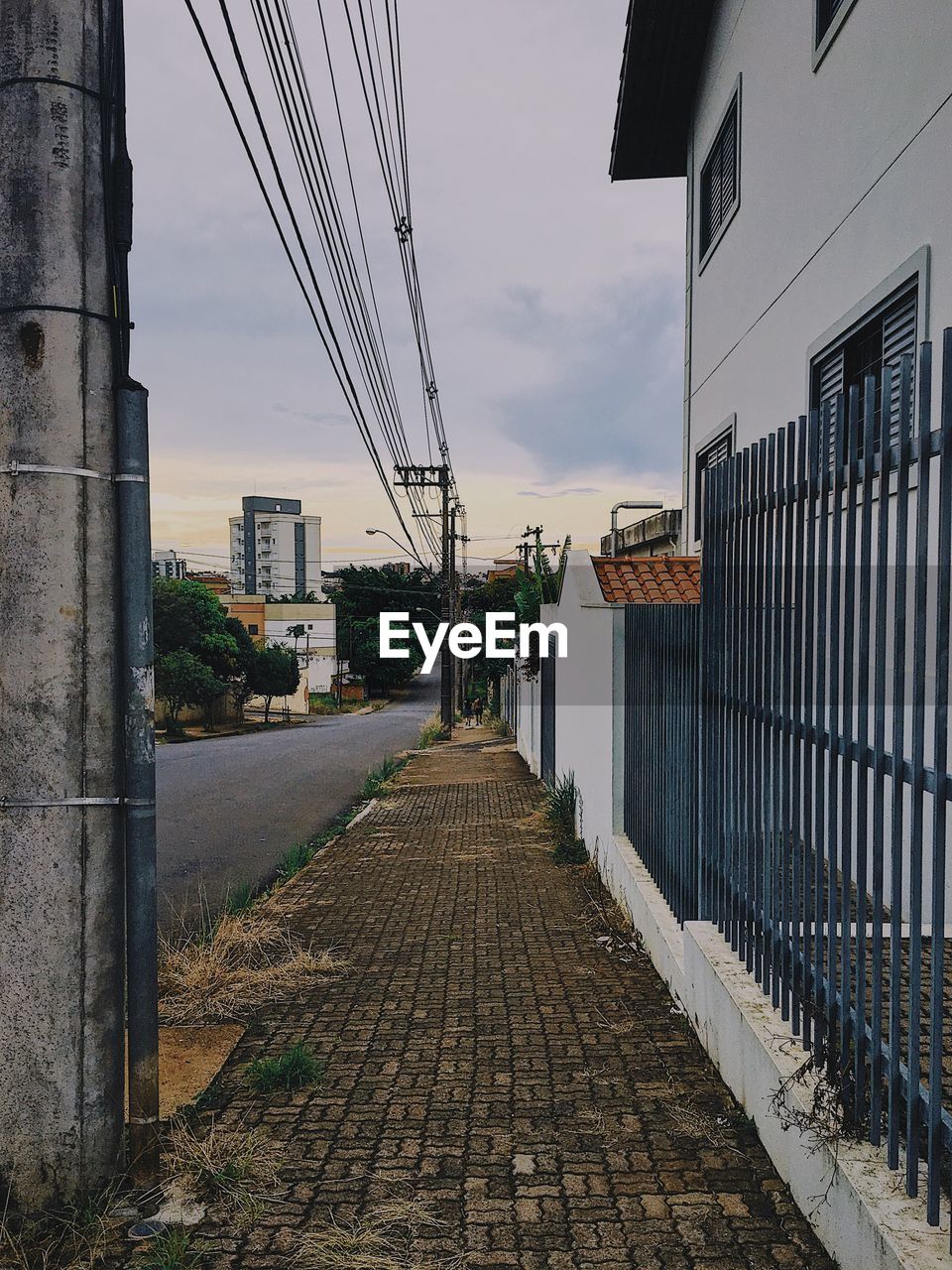 FOOTPATH AMIDST BUILDINGS AGAINST SKY