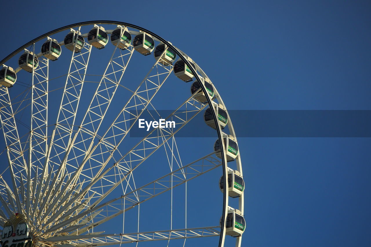 Low angle view of ferris wheel against blue sky