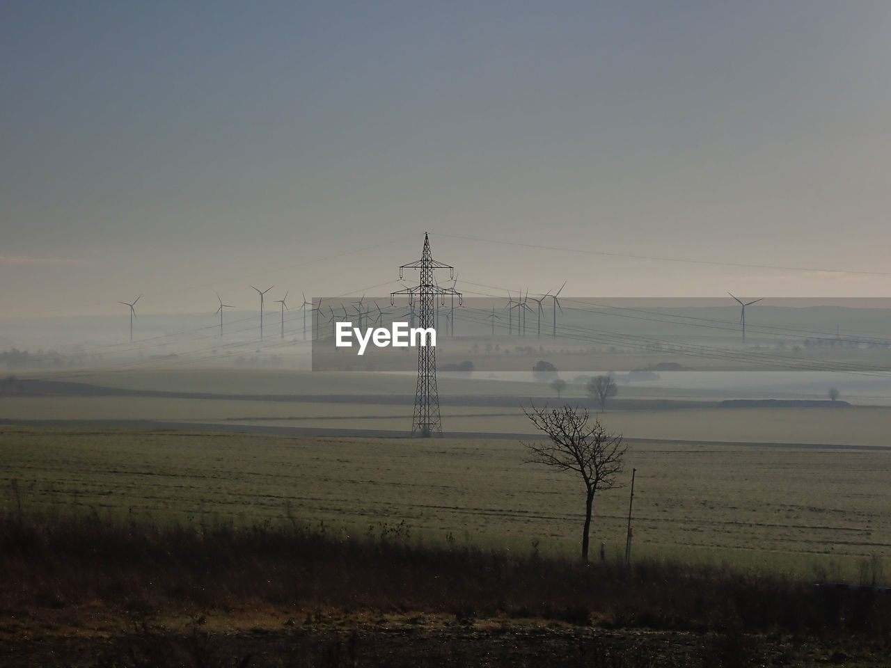 Electricity pylon on field against sky