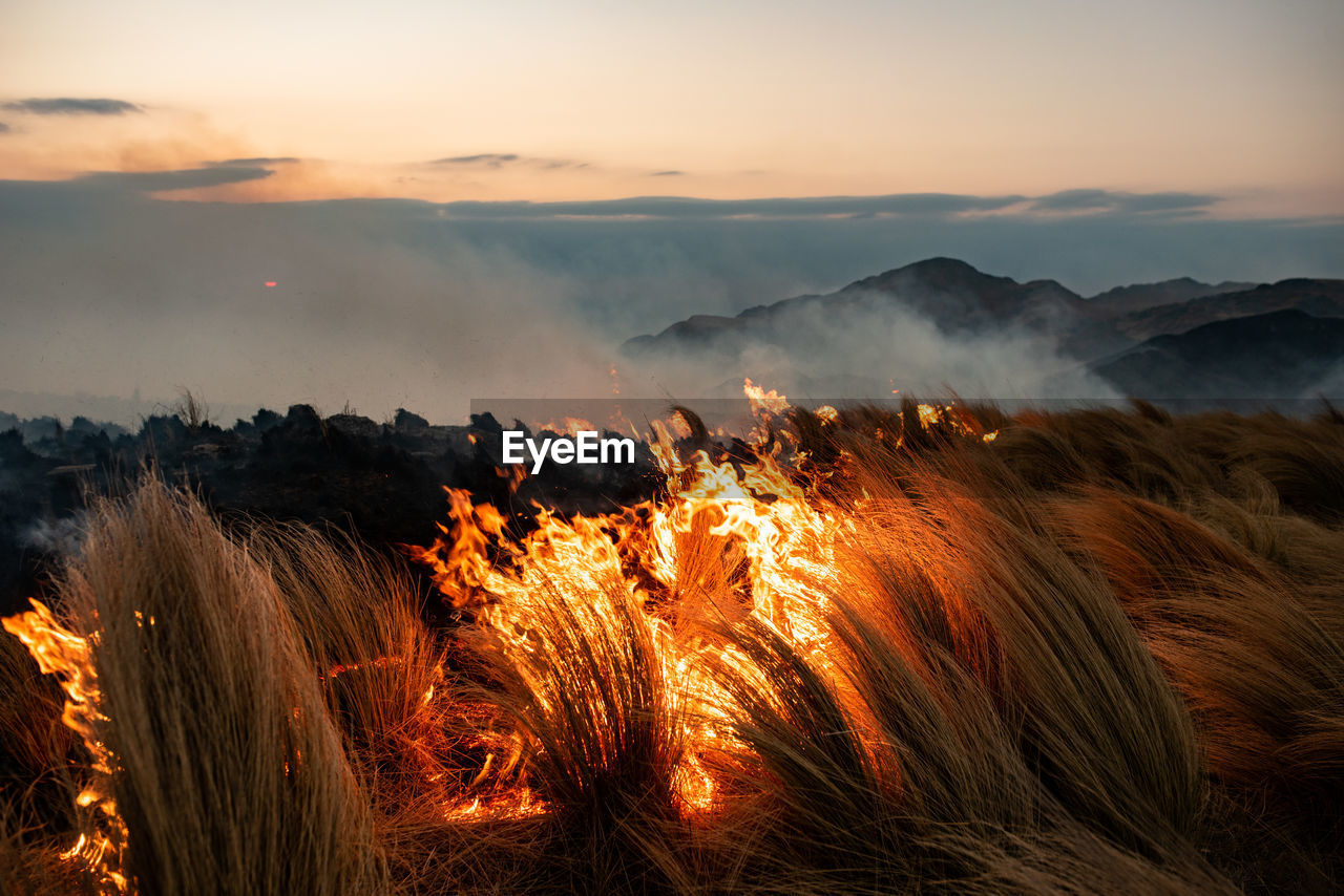 Panoramic view of bonfire on mountain against sky during sunset