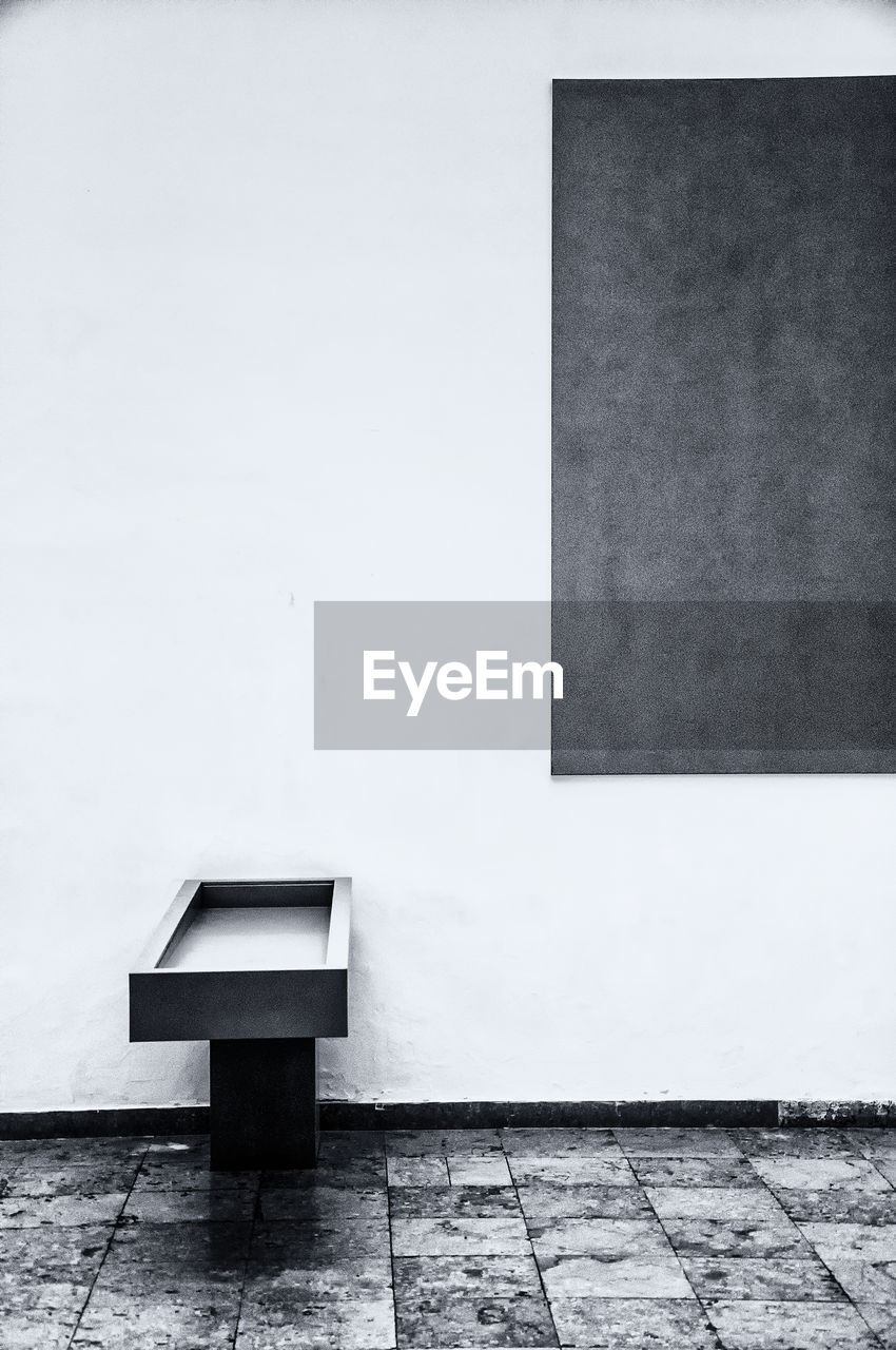 EMPTY BENCH AGAINST WHITE WALL