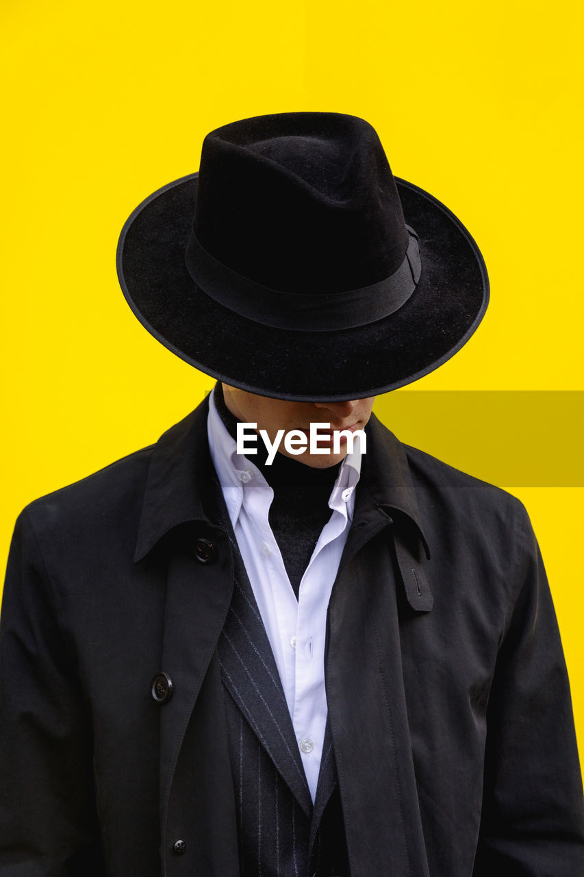 PORTRAIT OF MID ADULT MAN WEARING HAT AGAINST YELLOW BACKGROUND