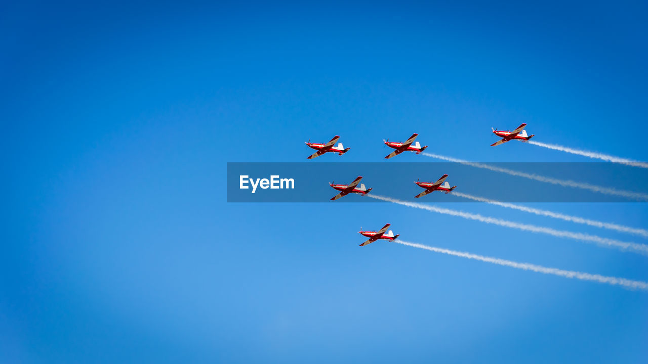 Low angle view of airshow against blue sky