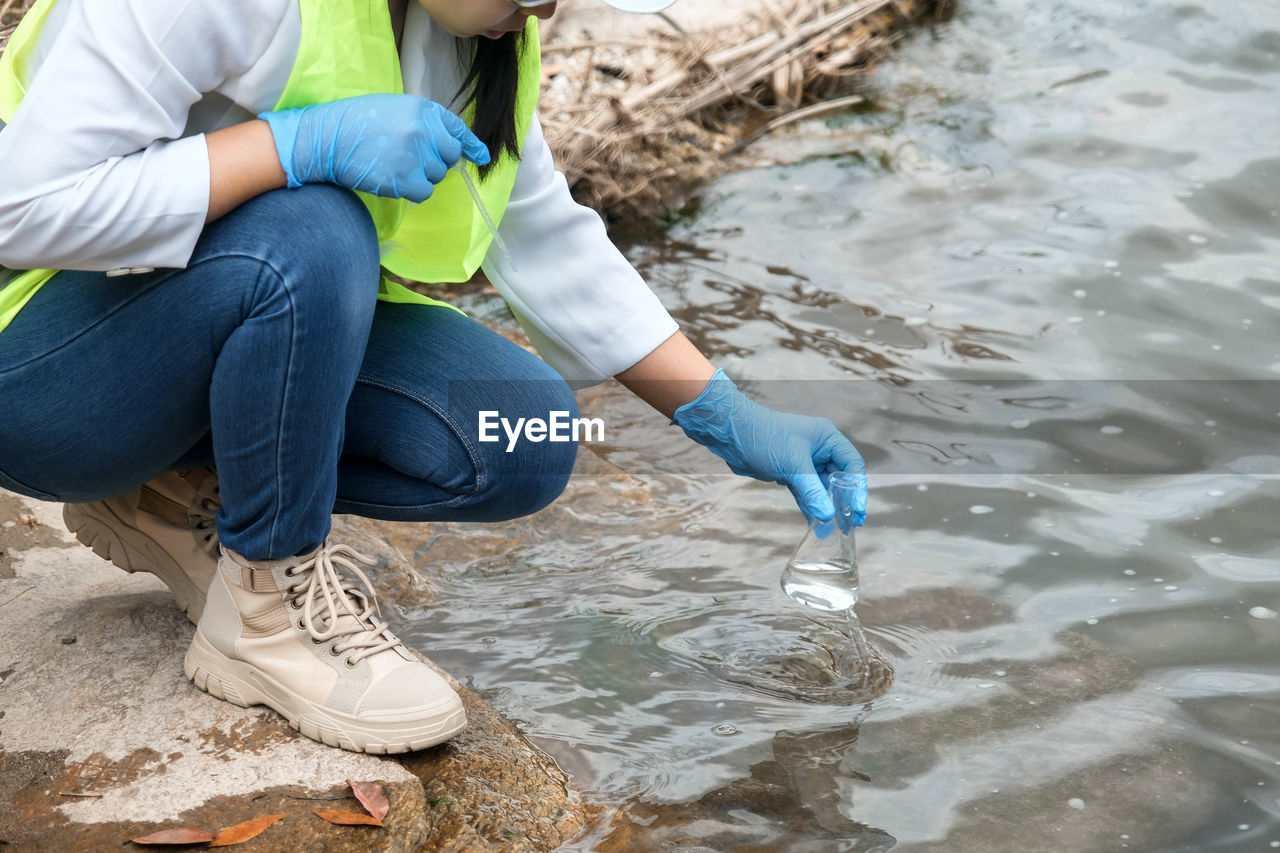 water, one person, nature, sitting, shoe, full length, child, adult, environment, day, casual clothing, childhood, rubber boot, women, leisure activity, footwear, boot, person, environmental issues, outdoors, protective workwear, spring, crouching, protection, clothing, lifestyles, female, men, land, dirt, protective glove, beach