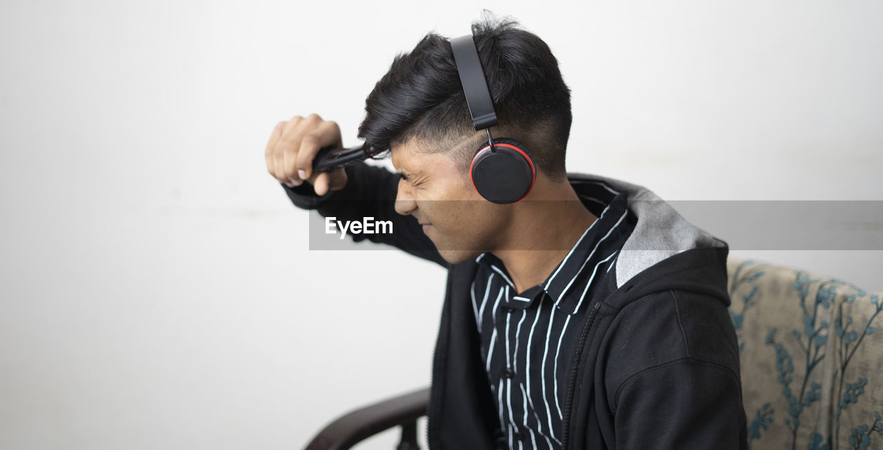Asian man with headphone wearing black jacket holding remote while sad expression face cheering.