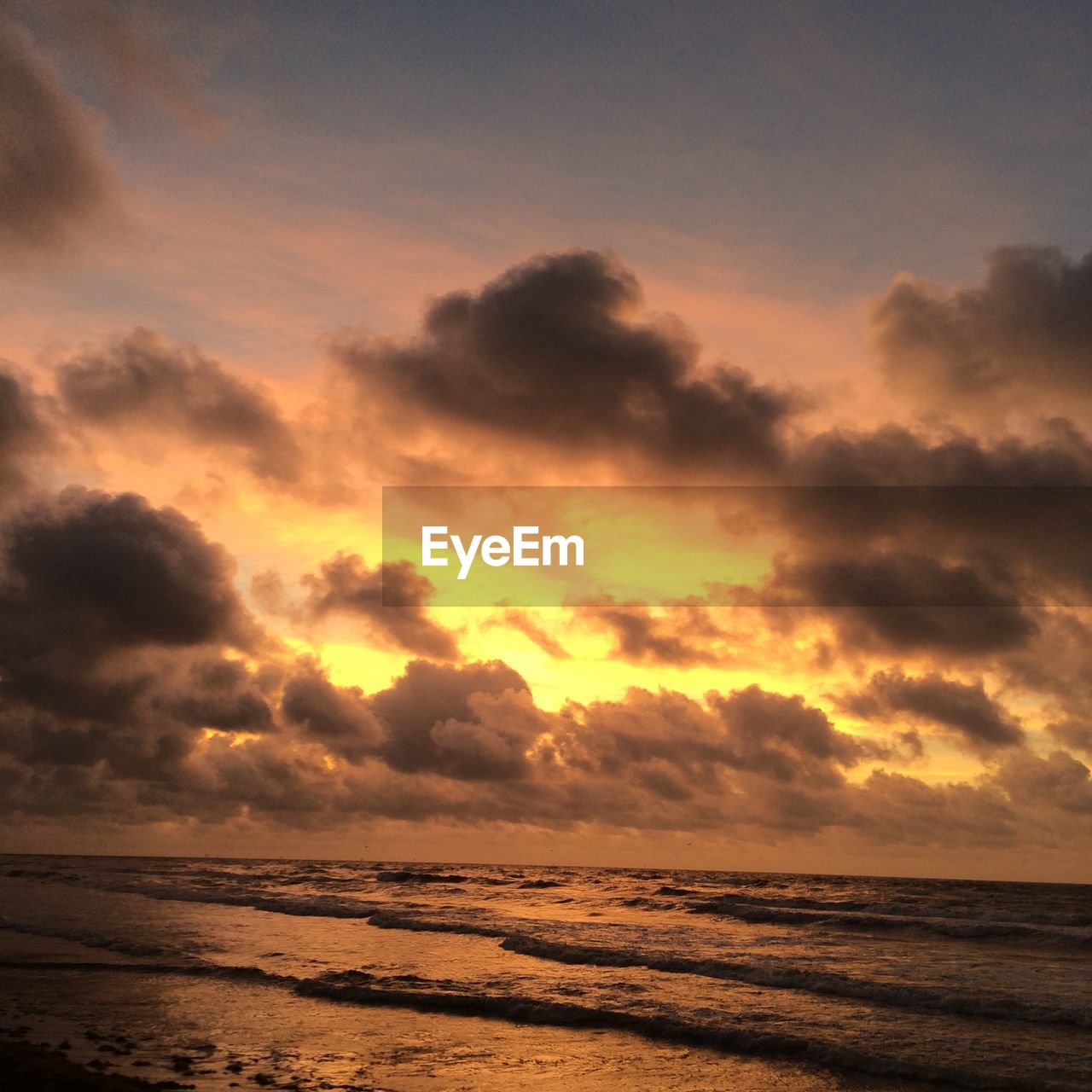 Scenic view of sea against cloudy sky during sunset