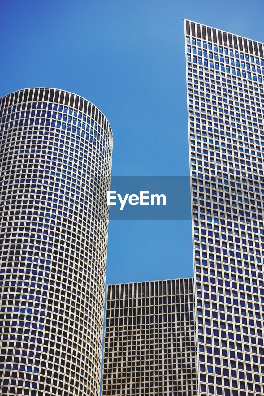 Low angle view of modern buildings against clear blue sky