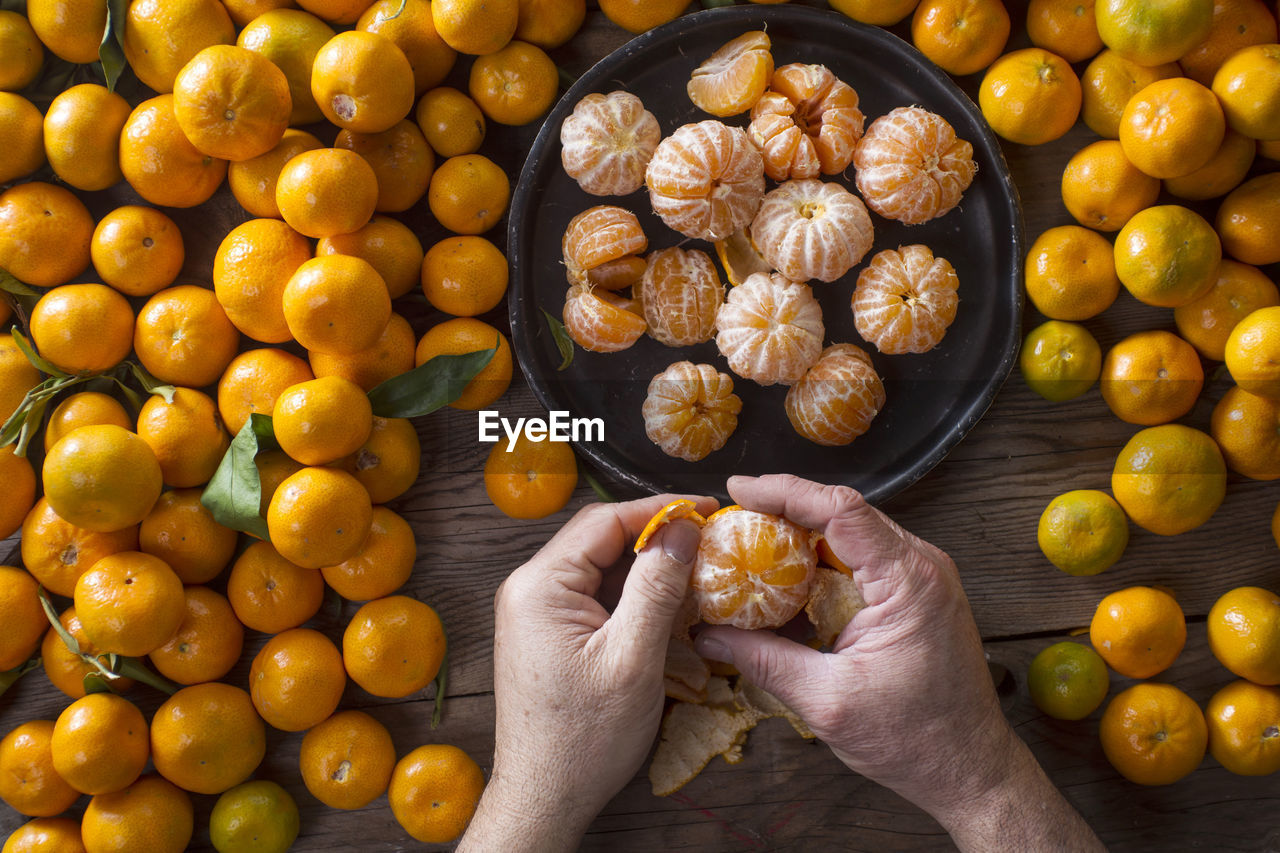 Cropped image of man peeling orange