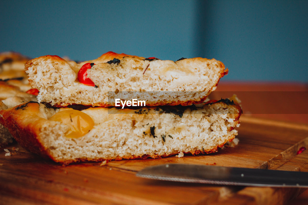 
homemade italian focaccia slices, with tomato and olive oil on a rustic wooden background.