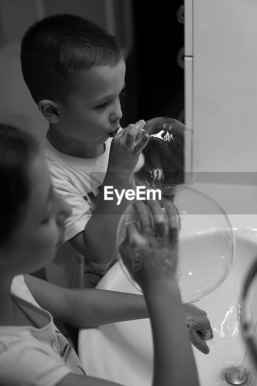 High angle view of siblings blowing bubbles in bathroom