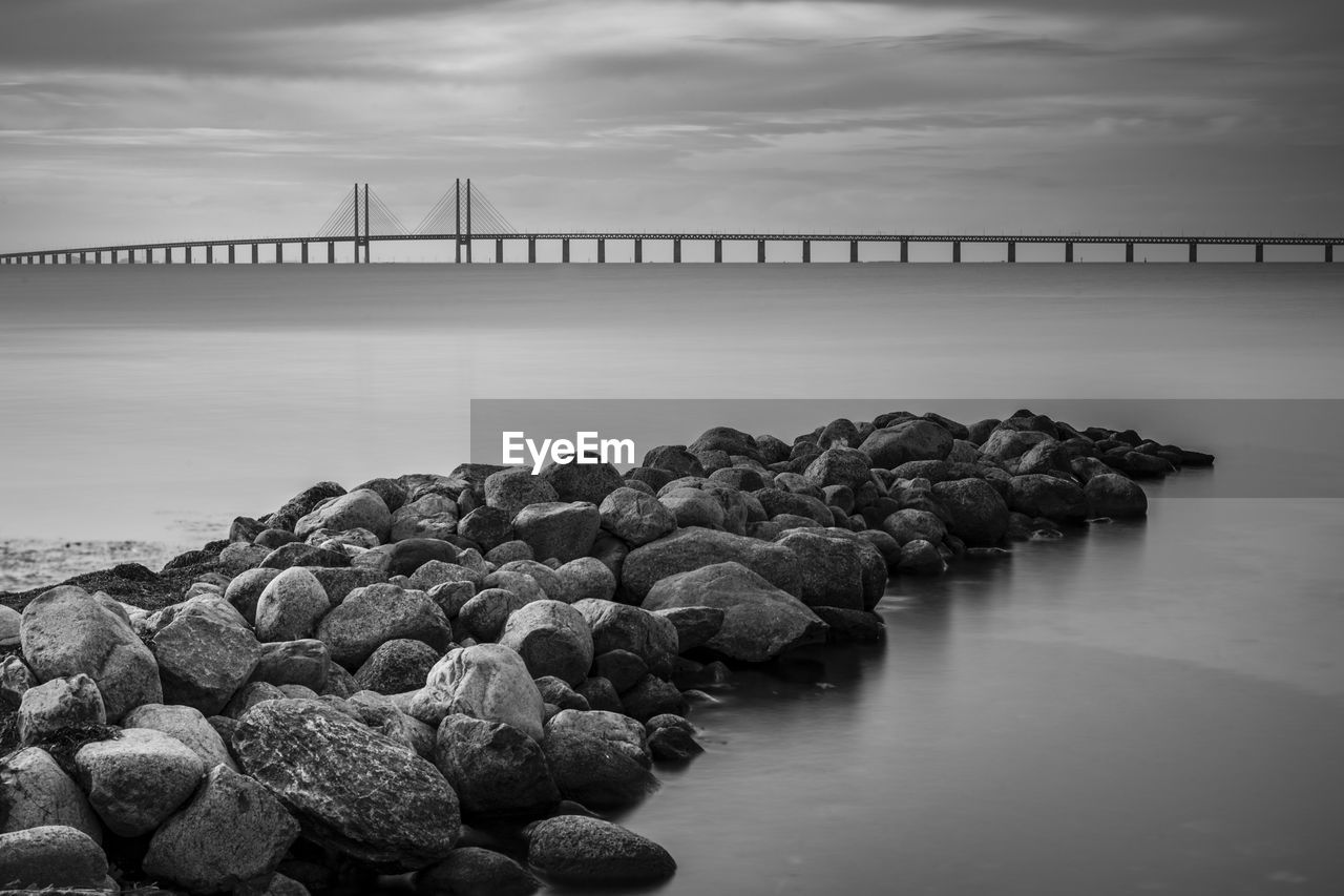 Öresund bridge over rocks in sea against sky