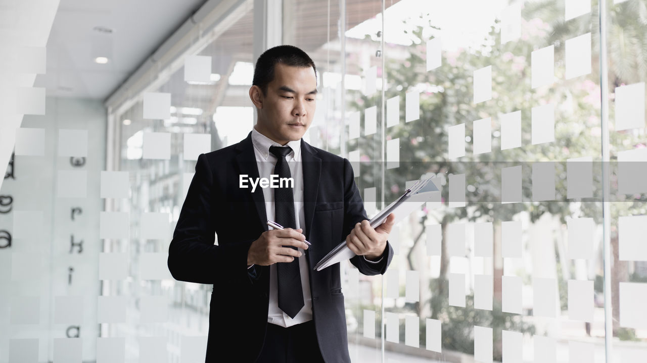 Businessman holding document while standing in office