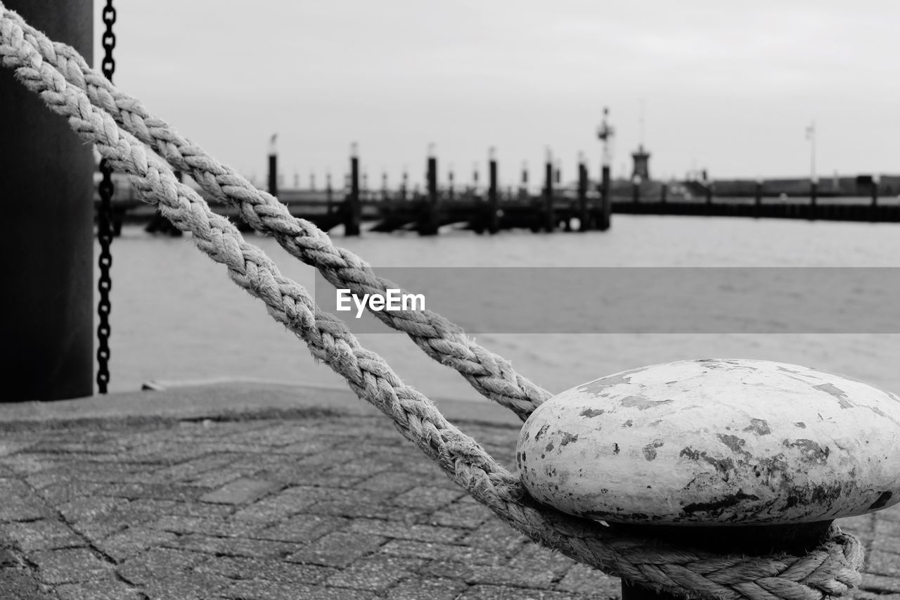 Close-up of rope tied up on bollard at harbor