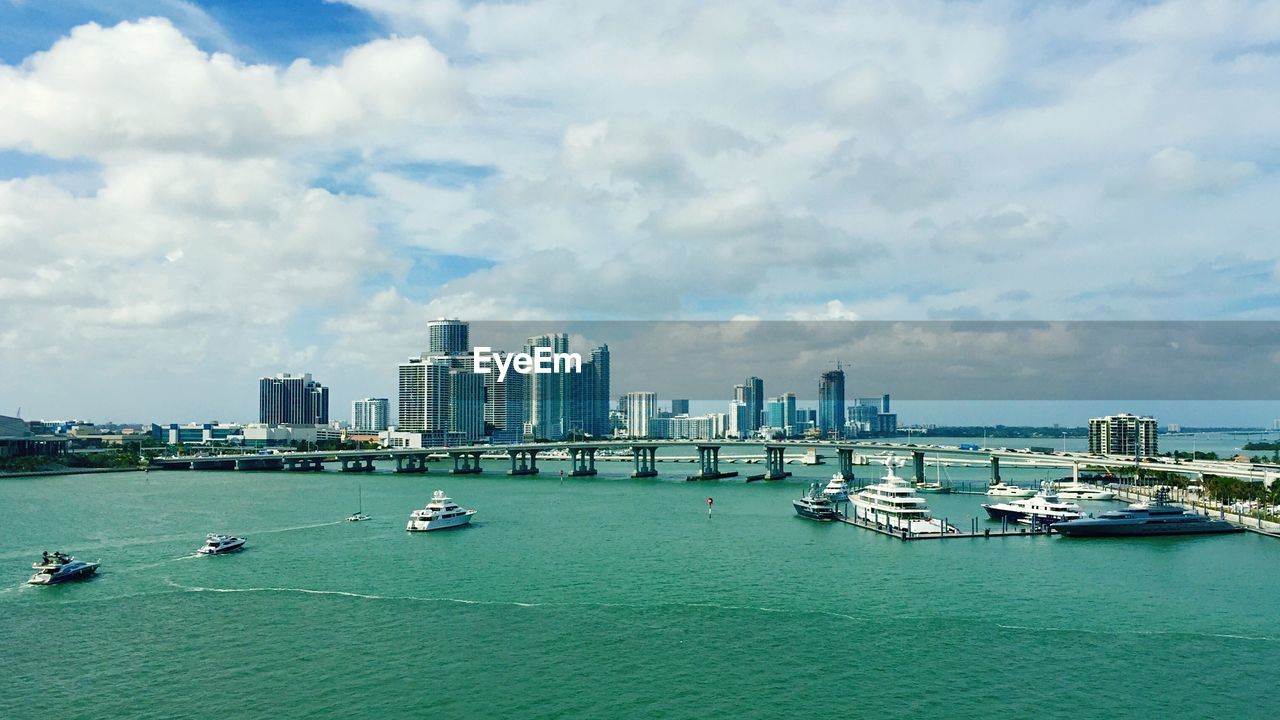 Boats at harbor against cloudy sky