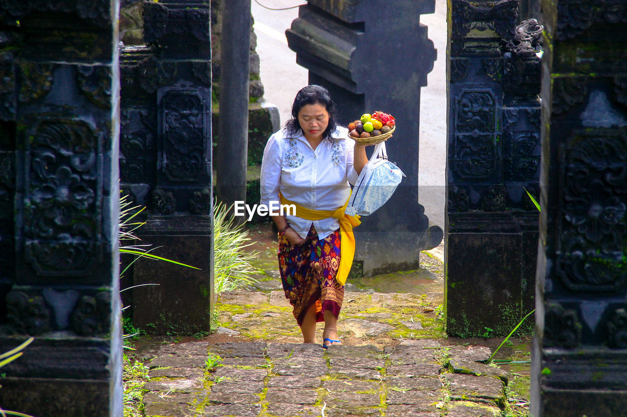 Full length of woman carrying fruits in temple