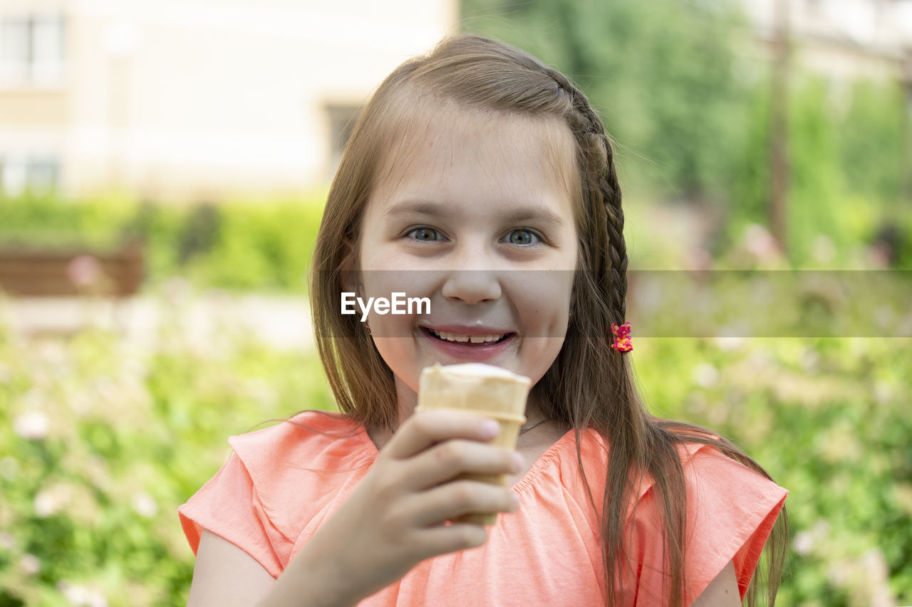 Portrait of smiling girl eating ice cream outdoors