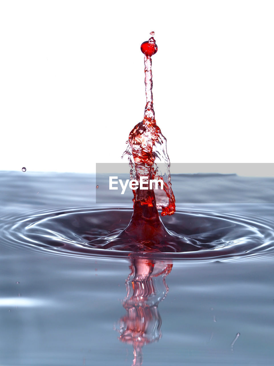 Close-up of red water splashing against white background