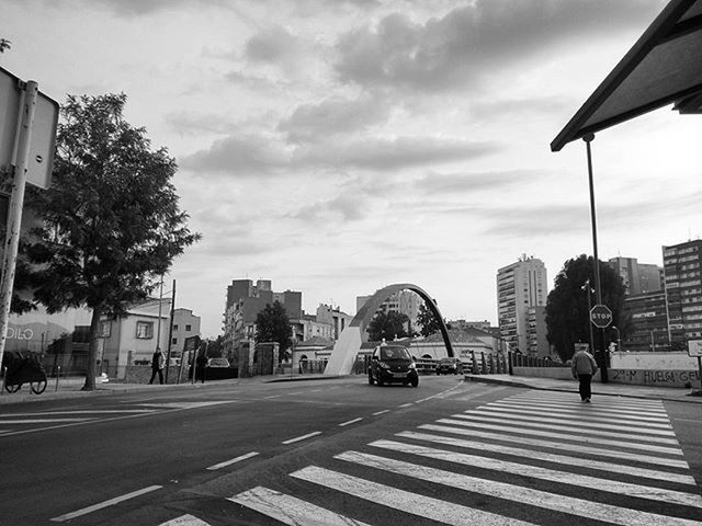 PEOPLE WALKING ON CITY STREET AGAINST CLOUDY SKY