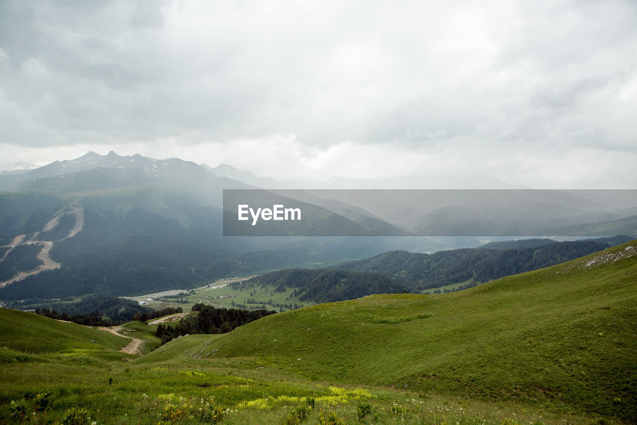 Green slope of a high mountain during a thunderstorm with clouds in the sky