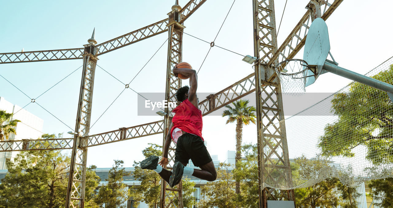 low angle view of man walking on cable against sky