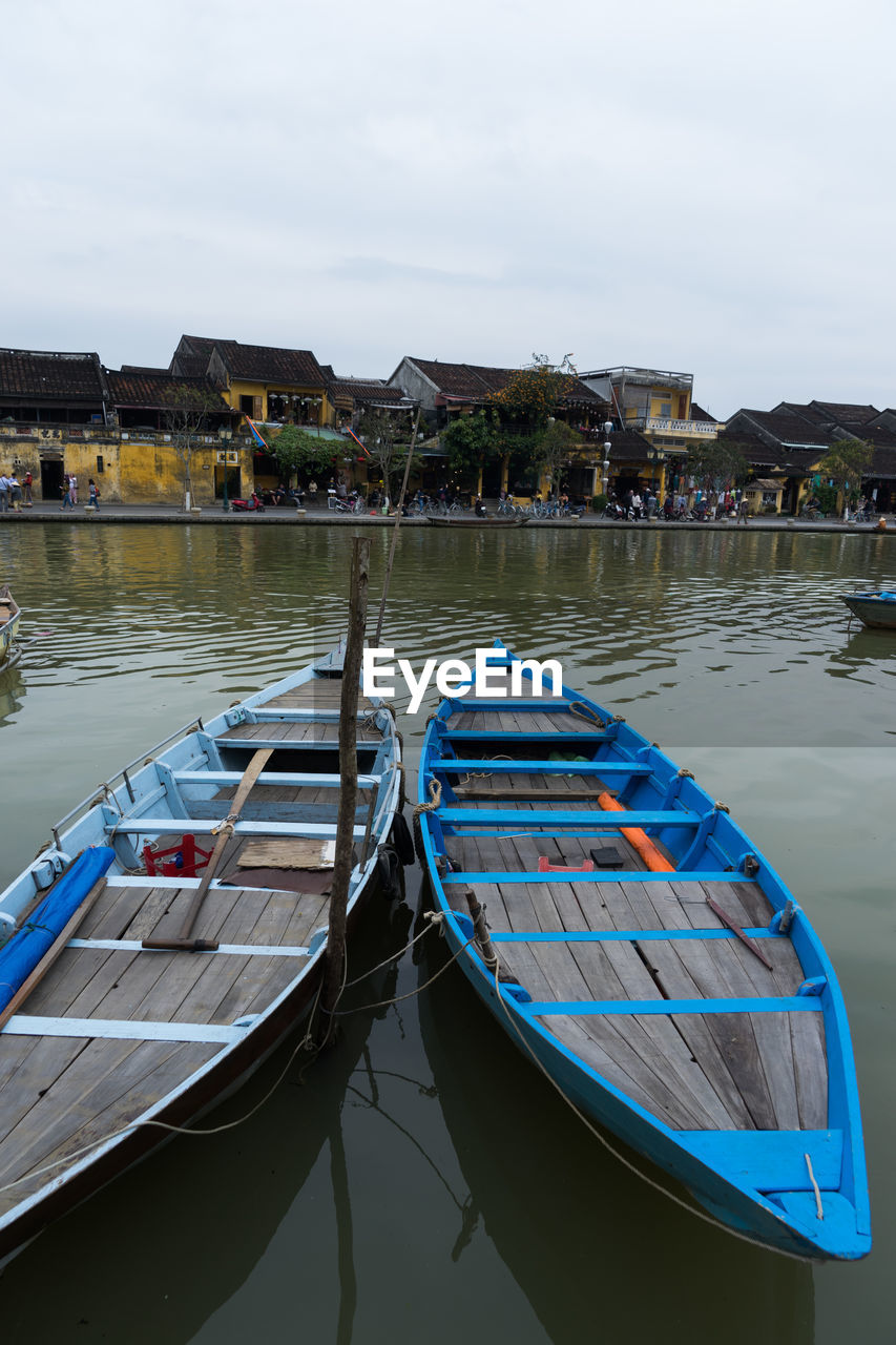 BOATS MOORED IN LAKE AGAINST SKY