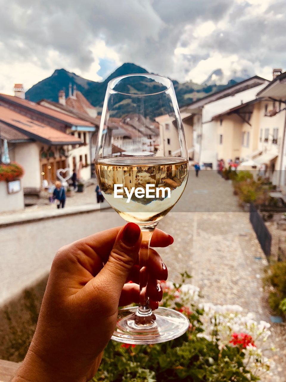 Cropped hand of woman holding wineglass against houses in town