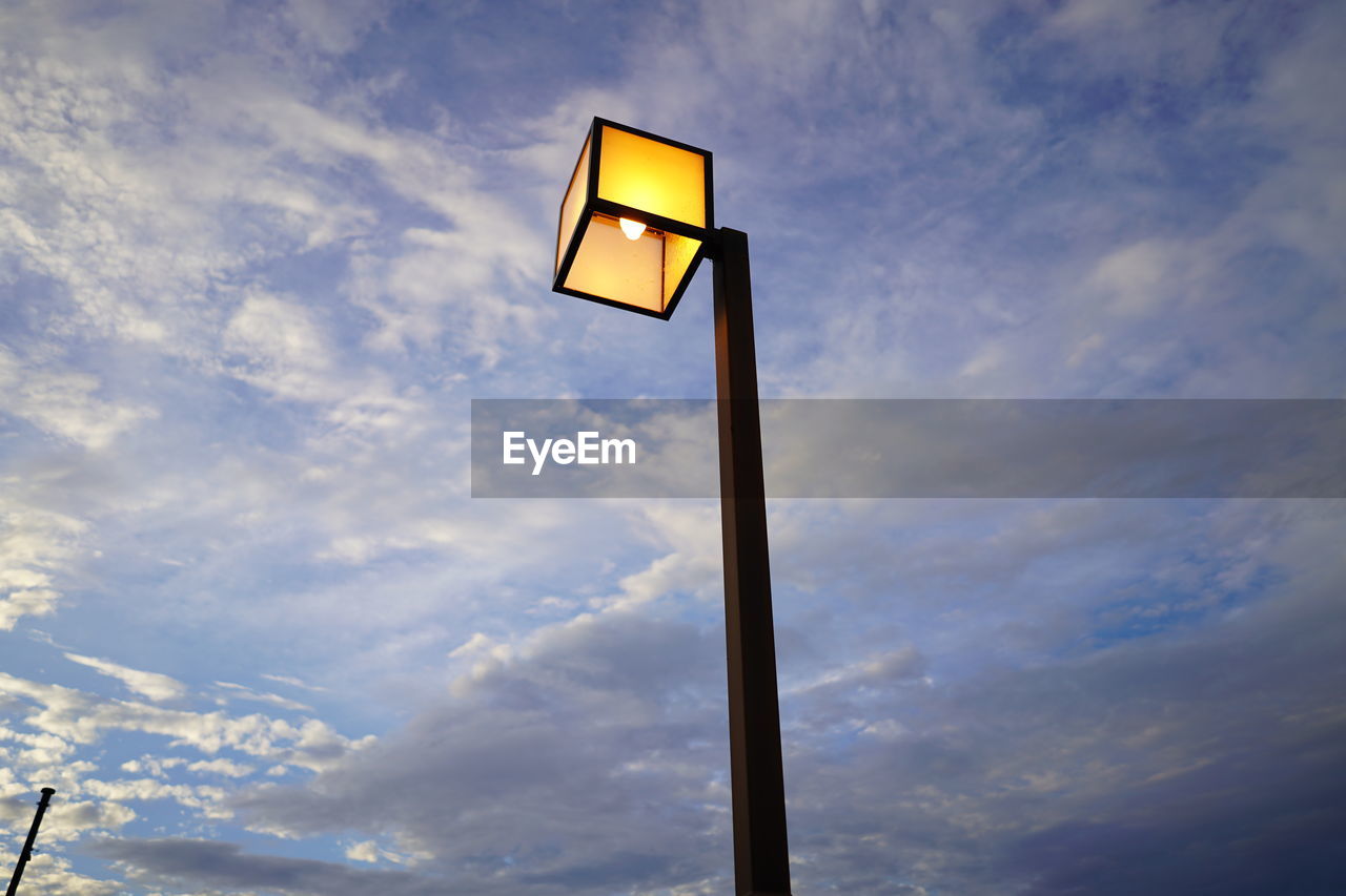 Low angle view of illuminated street light against cloudy sky