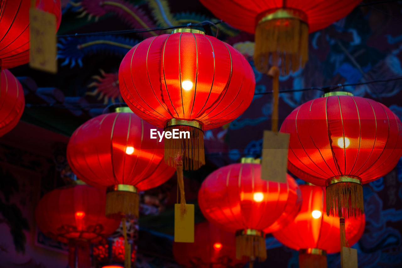 LOW ANGLE VIEW OF ILLUMINATED LANTERNS HANGING IN NIGHT