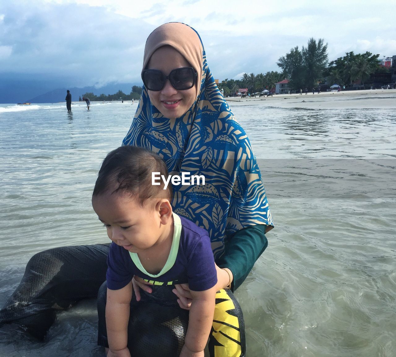 Portrait of happy mother holding son at beach