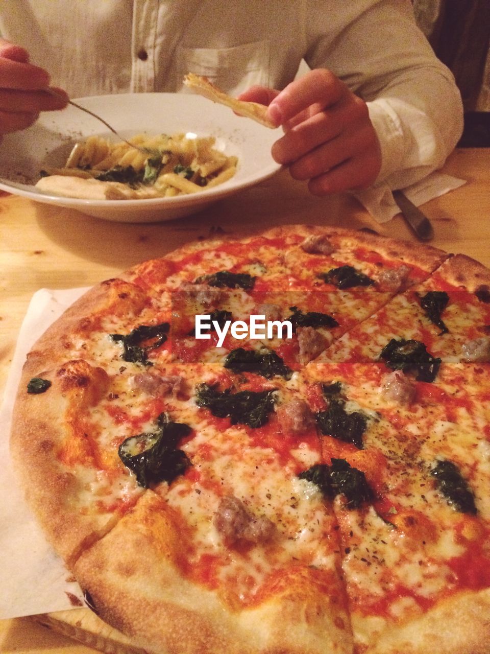 Close-up of pizza with person eating pasta