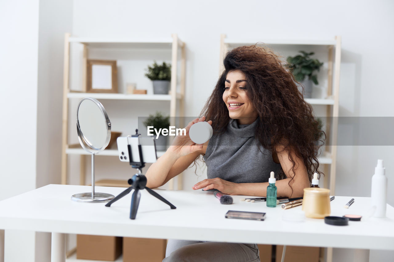 portrait of young woman using mobile phone while sitting on table