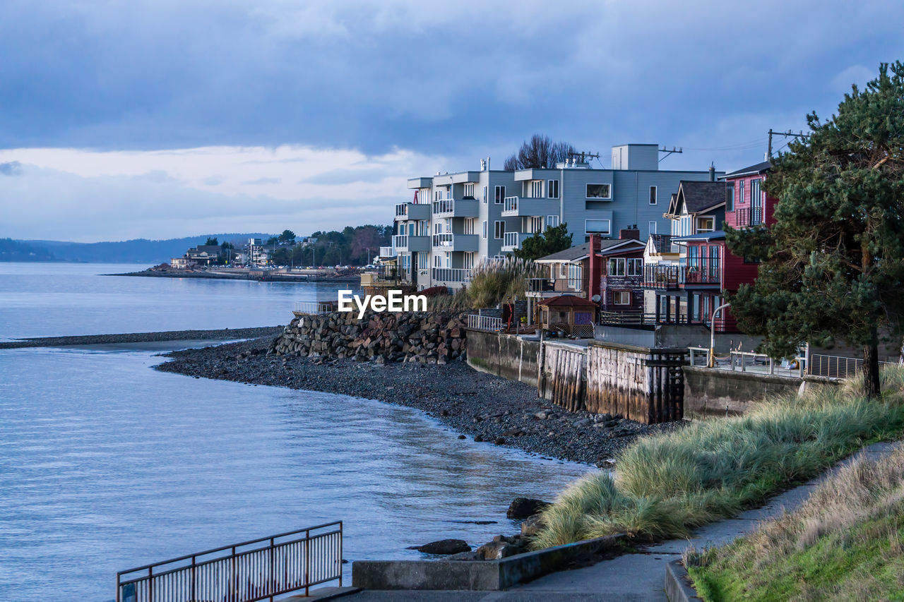 Buildings by sea against sky