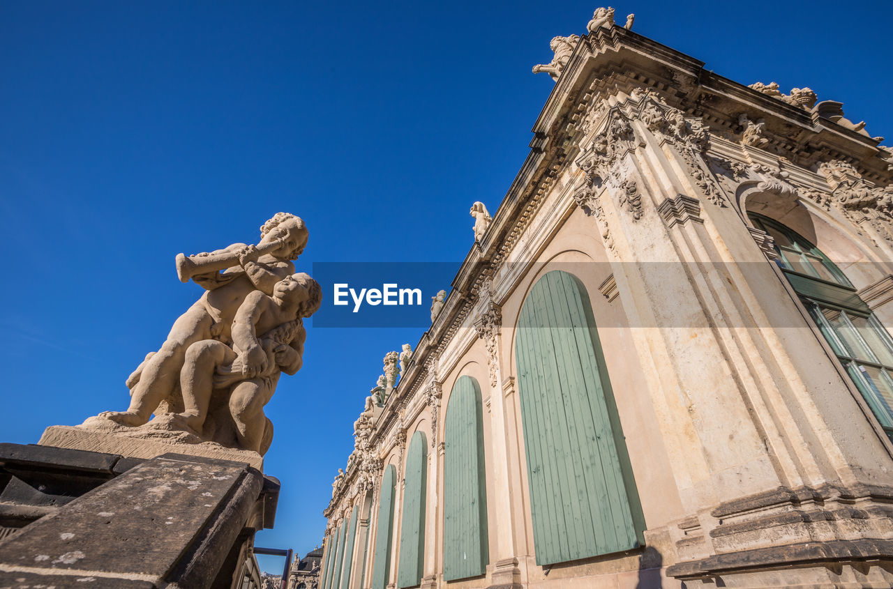 LOW ANGLE VIEW OF STATUE AGAINST BUILDING AGAINST SKY