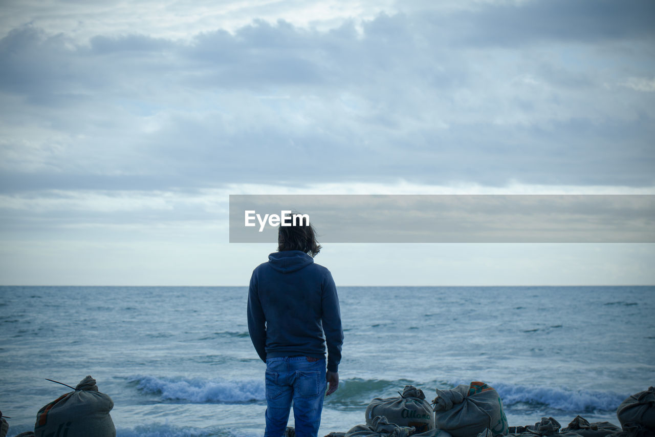 Rear view of man looking at sea against sky