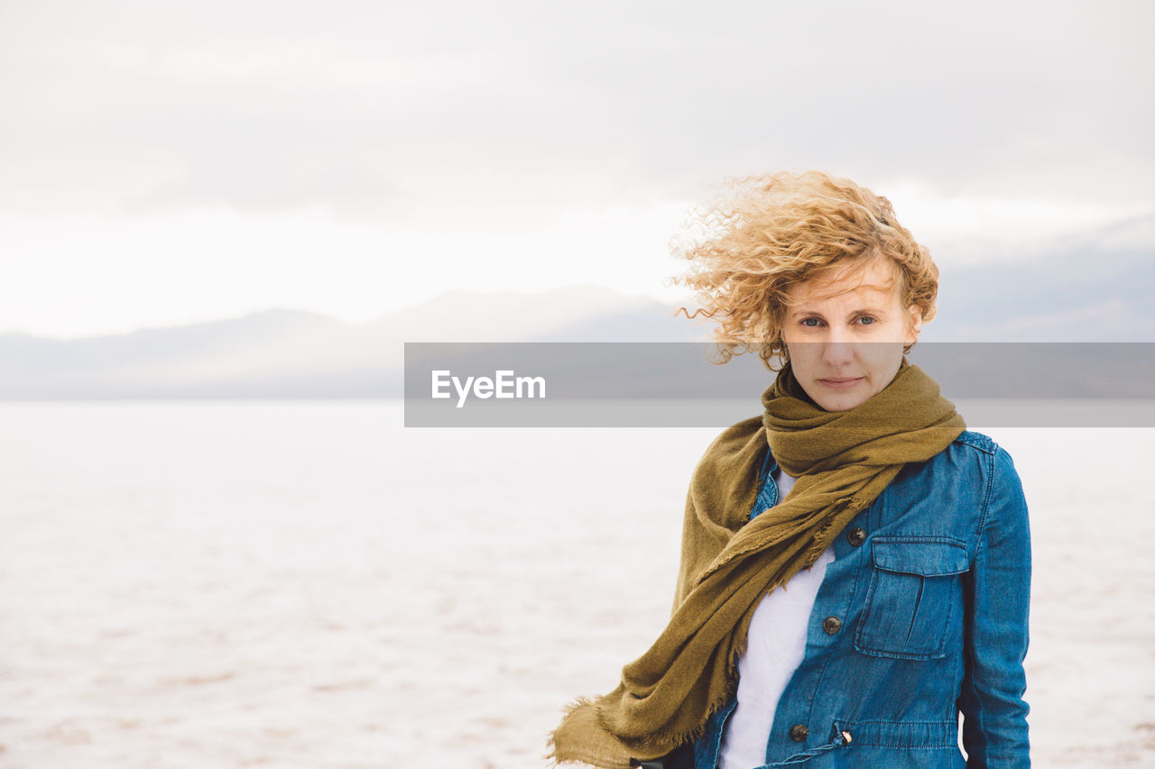 Portrait of young woman standing at death valley national park against cloudy sky