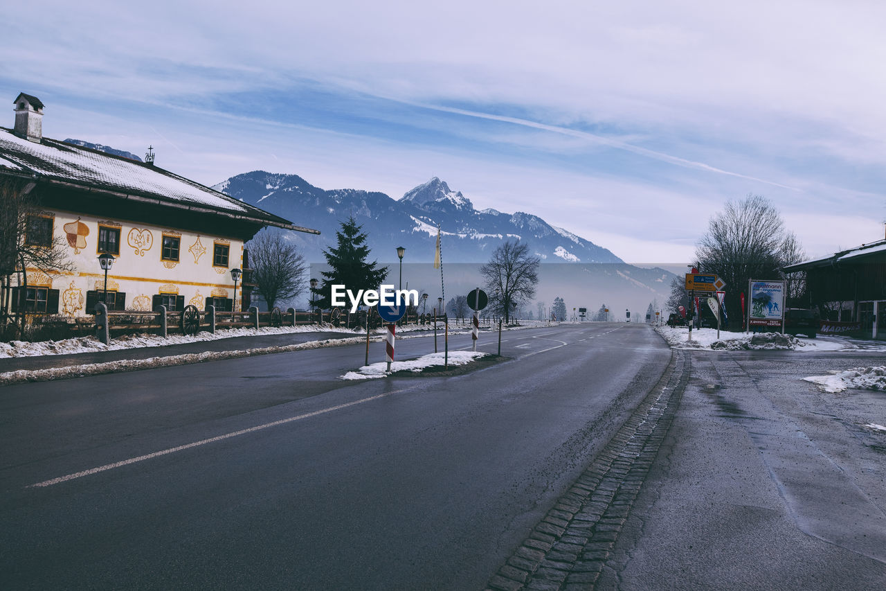 Road by mountains against sky during winter