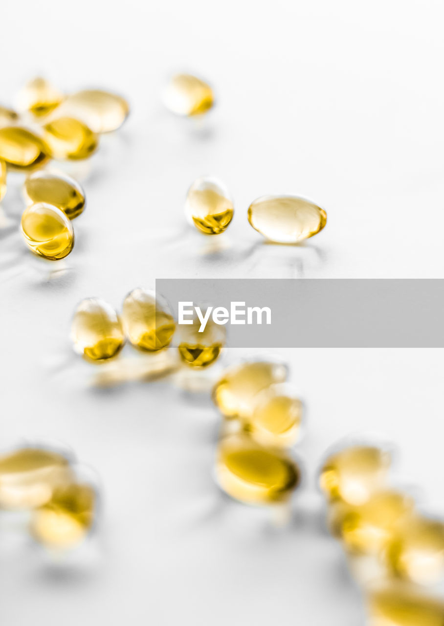 close-up of pills spilling from bottle against white background