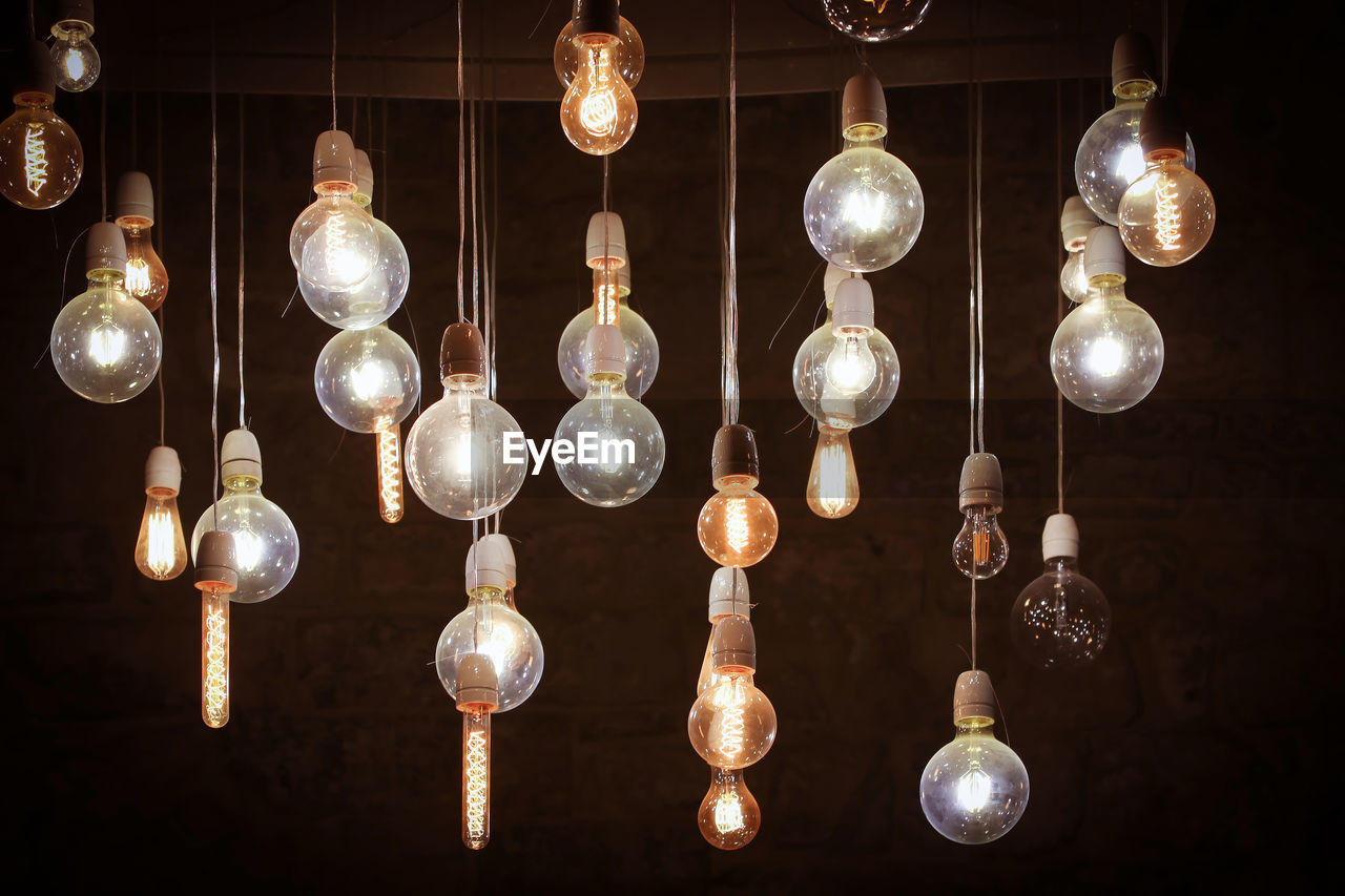 Low angle view of illuminated pendant lights hanging on ceiling