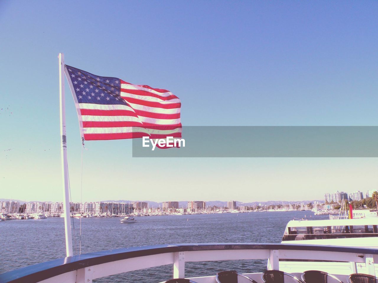 American flag on boat against clear sky