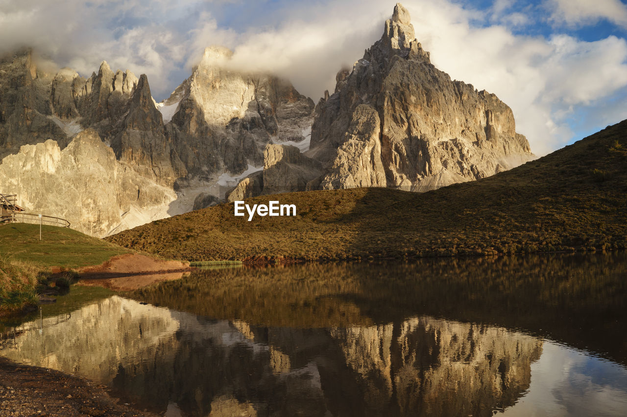 Scenic view of lake by mountains against cloudy sky