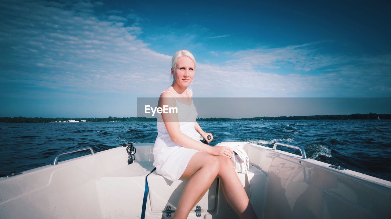 Woman sitting on boat sailing in sea against sky
