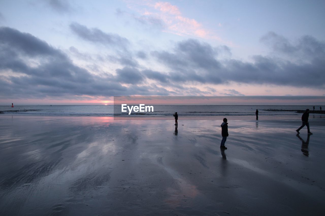 PEOPLE PLAYING ON BEACH AGAINST SKY