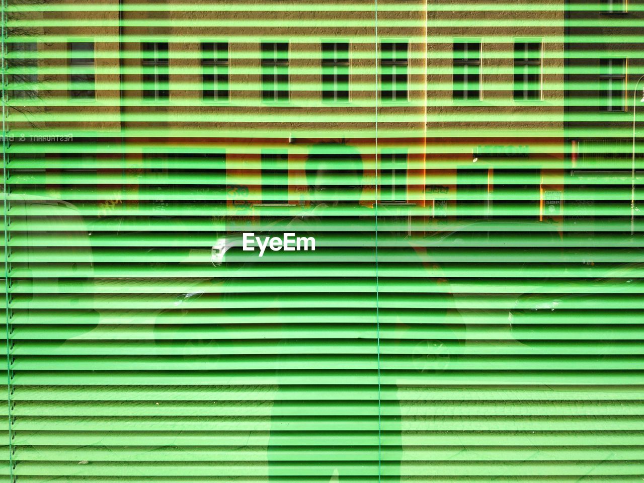 Man seen through green blinds