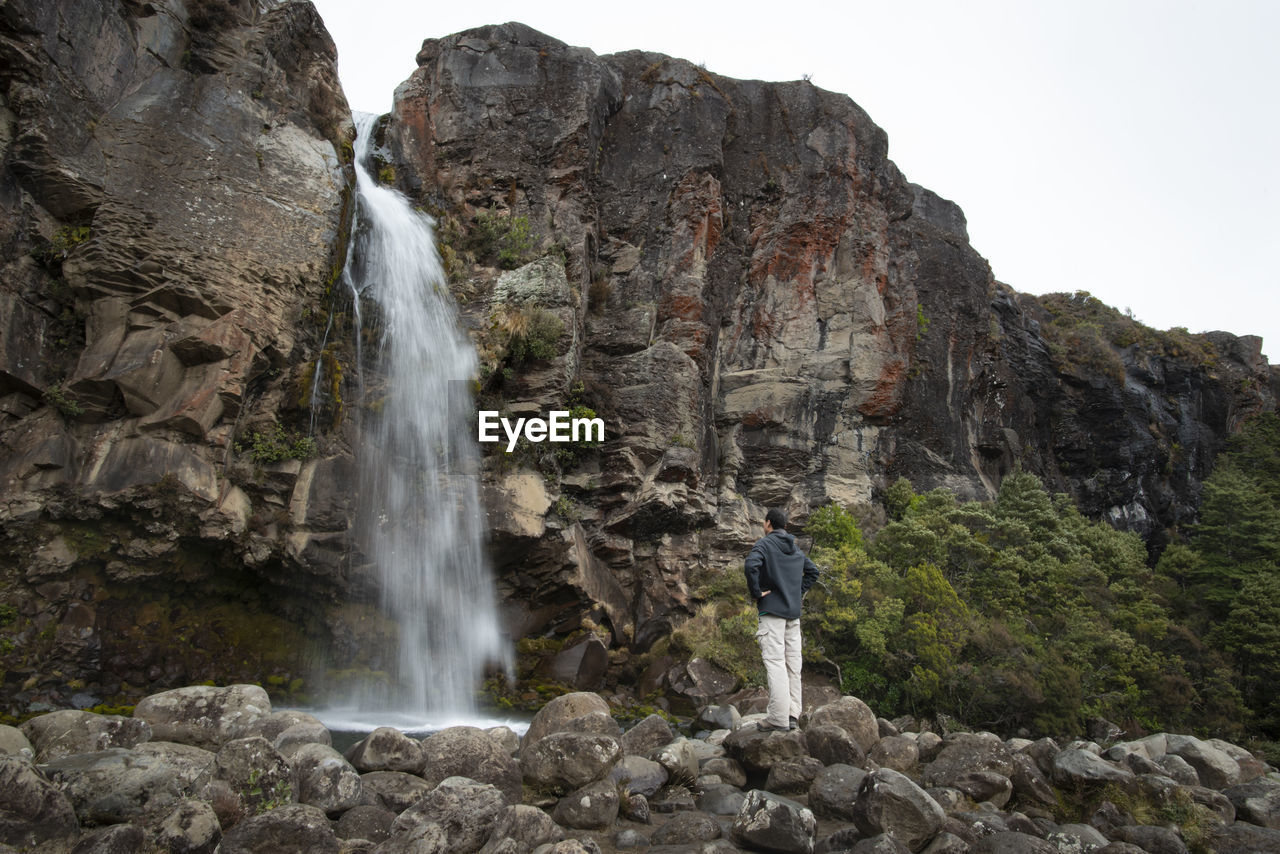 Full length of man looking at waterfall