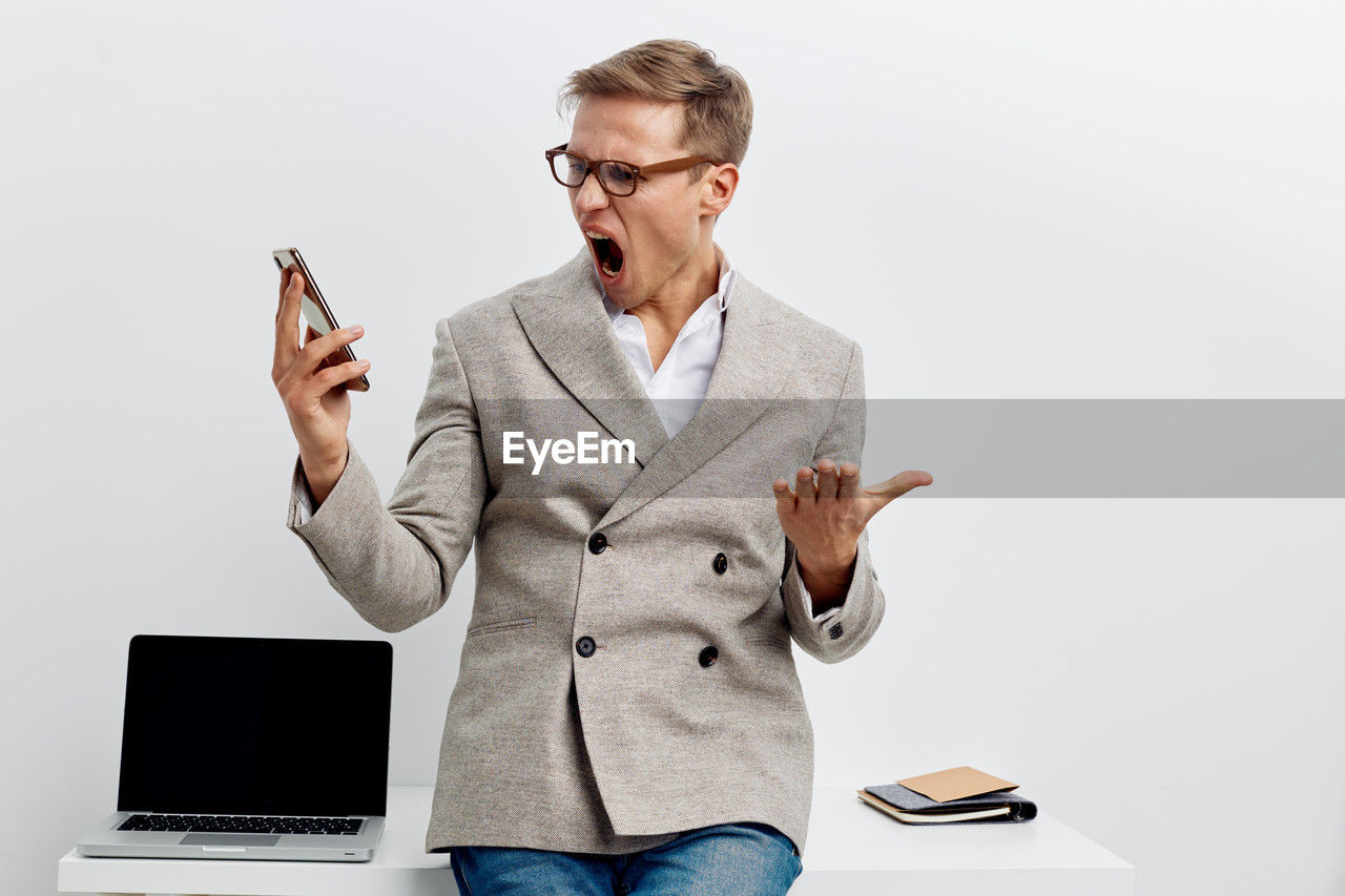 portrait of young man using digital tablet while standing against white background